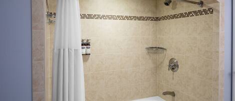 A modern bathroom with a bathtub, shower, and tiled walls.