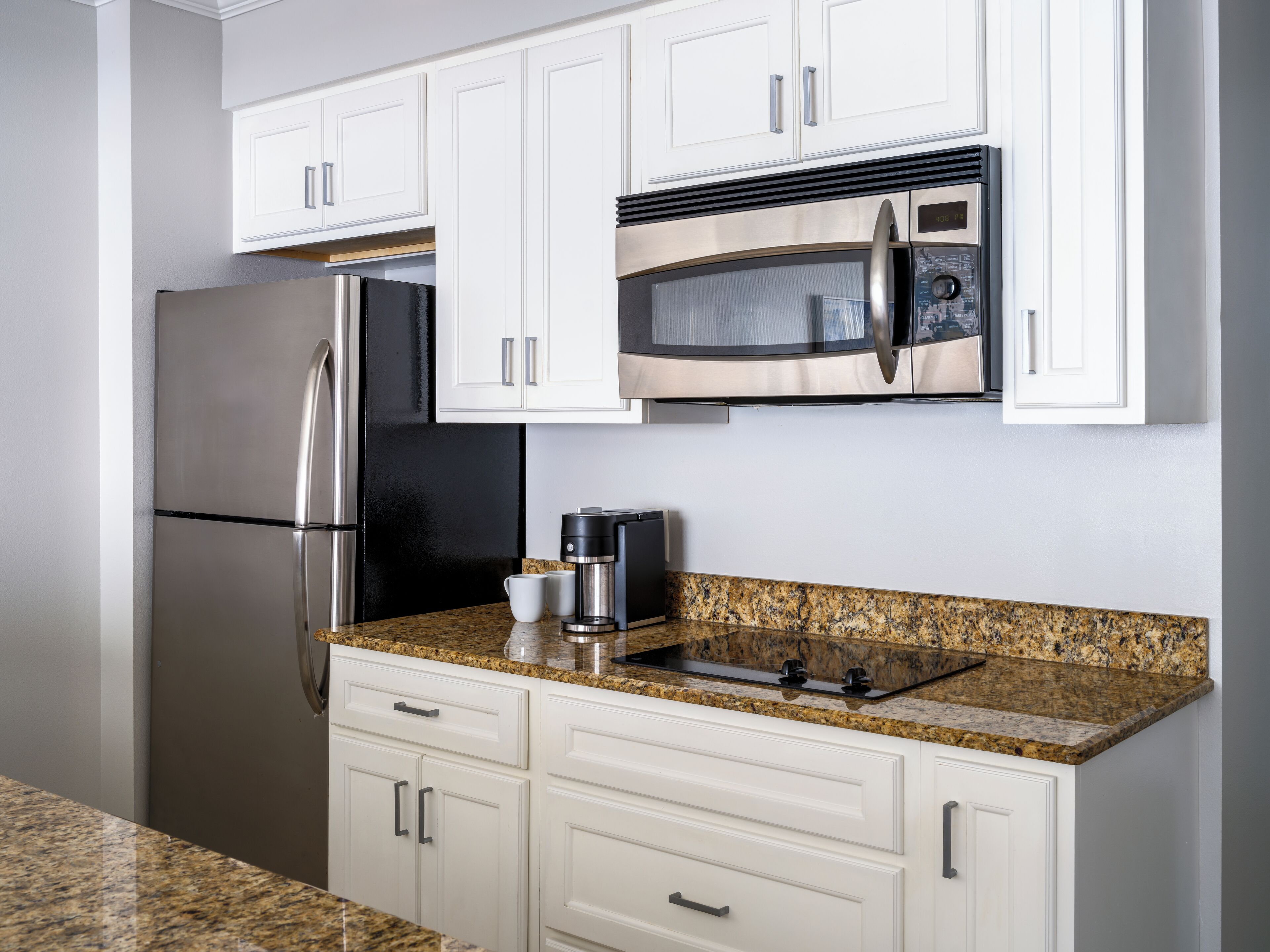 A modern kitchen with white cabinets, stainless steel appliances, and granite countertops.