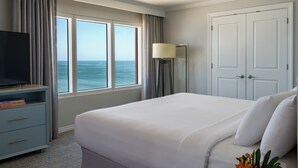 A hotel room with a large bed, a TV on a stand, a desk with a lamp, and a view of the ocean. - Hyatt Regency Clearwater Beach Resort and Suites (Clearwater Beach)
