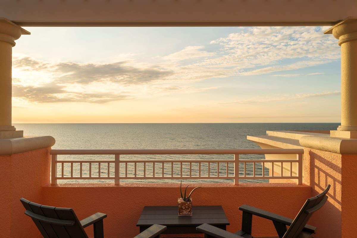 A balcony with a view of the sea during sunset.
