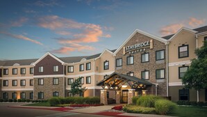 A multi-story hotel with a stone facade and a sign reading 'STAYBRIDGE SUITES'.