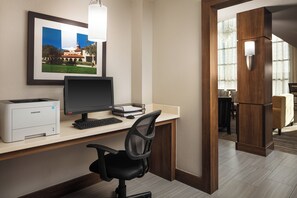 Ein Hotelbüro mit Schreibtisch, Computer, Drucker und gerahmtem Bild.