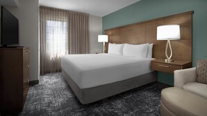 A hotel room with a large bed, two bedside tables with lamps, a television, a desk, and a chair.
