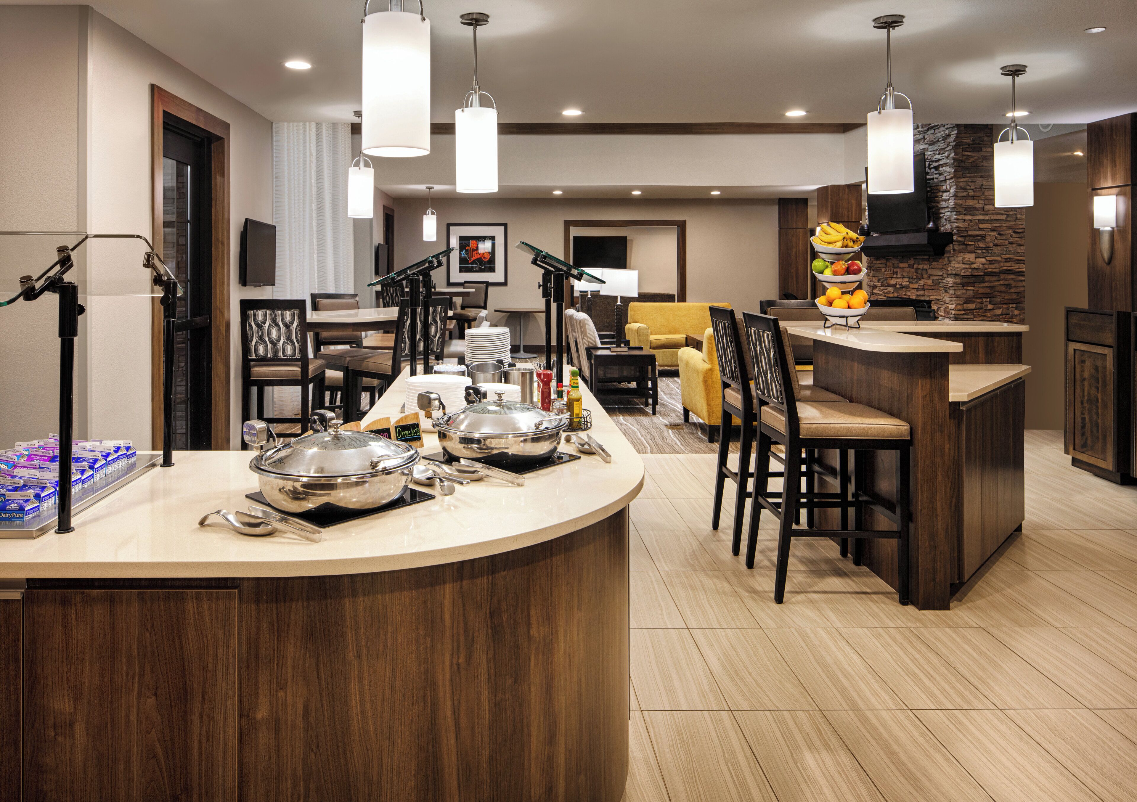Eine moderne Küche mit Bar, Essbereich und Wohnbereich, deren Wand einen Steinakzent aufweist.