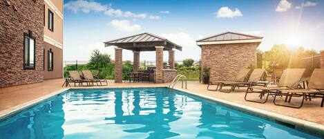 Una piscina con lettini e un gazebo.