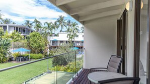 Ein Balkon mit Blick auf einen Pool, Palmen und andere Gebäude.