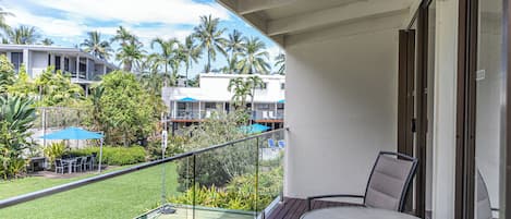 A balcony with a view of a pool, palm trees, and other buildings.
