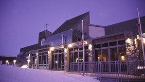 A modern building with a restaurant named "SnowGums" at its entrance, featuring large glass windows and stone pillars.