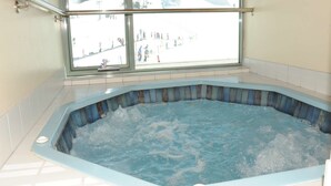 A hot tub with a view of a snowy landscape through a window.