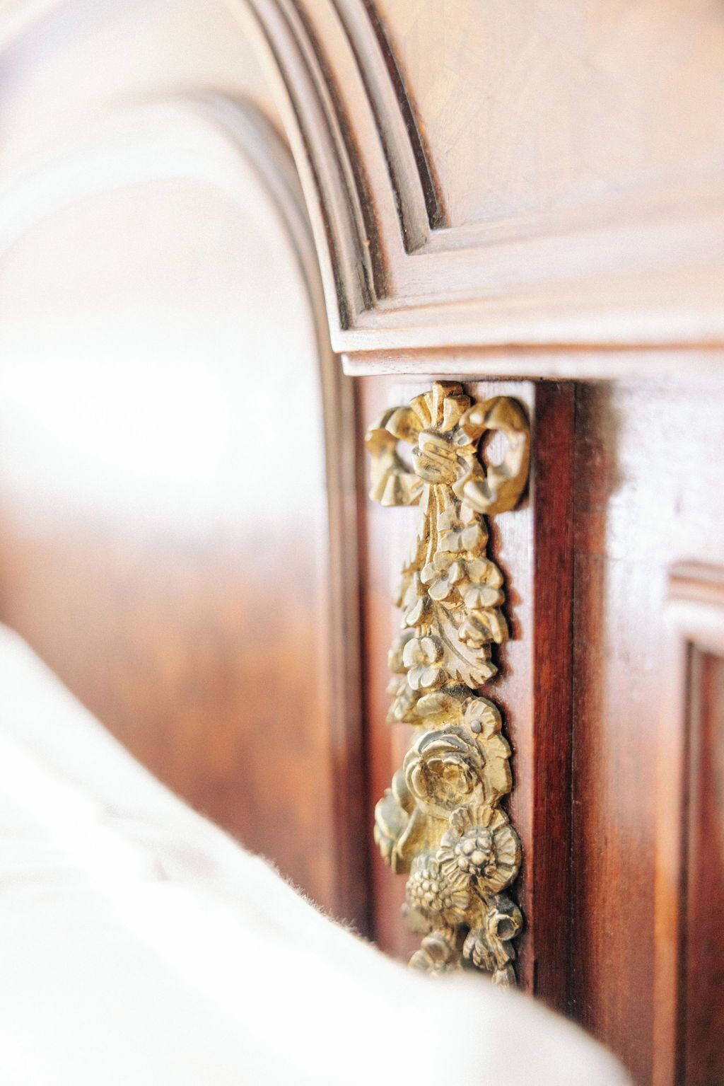 Close-up de uma estrutura de cama de madeira com detalhes florais dourados e elaborados.
