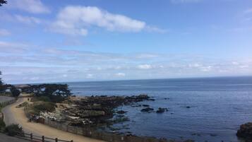 A coastal road with a paved path, rocky shoreline, and a clear view of the sea.