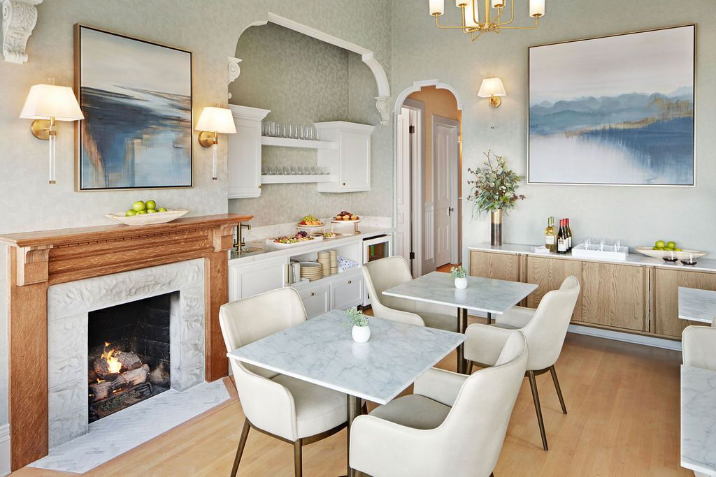 A modern dining area with a fireplace, marble tables, and white chairs.