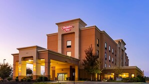Un hôtel Hampton Inn doté d’une façade moderne, de plusieurs entrées et d’un hall d’entrée bien éclairé.
