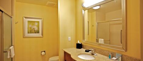 A bathroom with a sink, mirror, toilet, and framed picture on the wall.