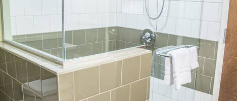 A modern bathroom with a glass-enclosed shower, beige and white tiles, and a glass partition.