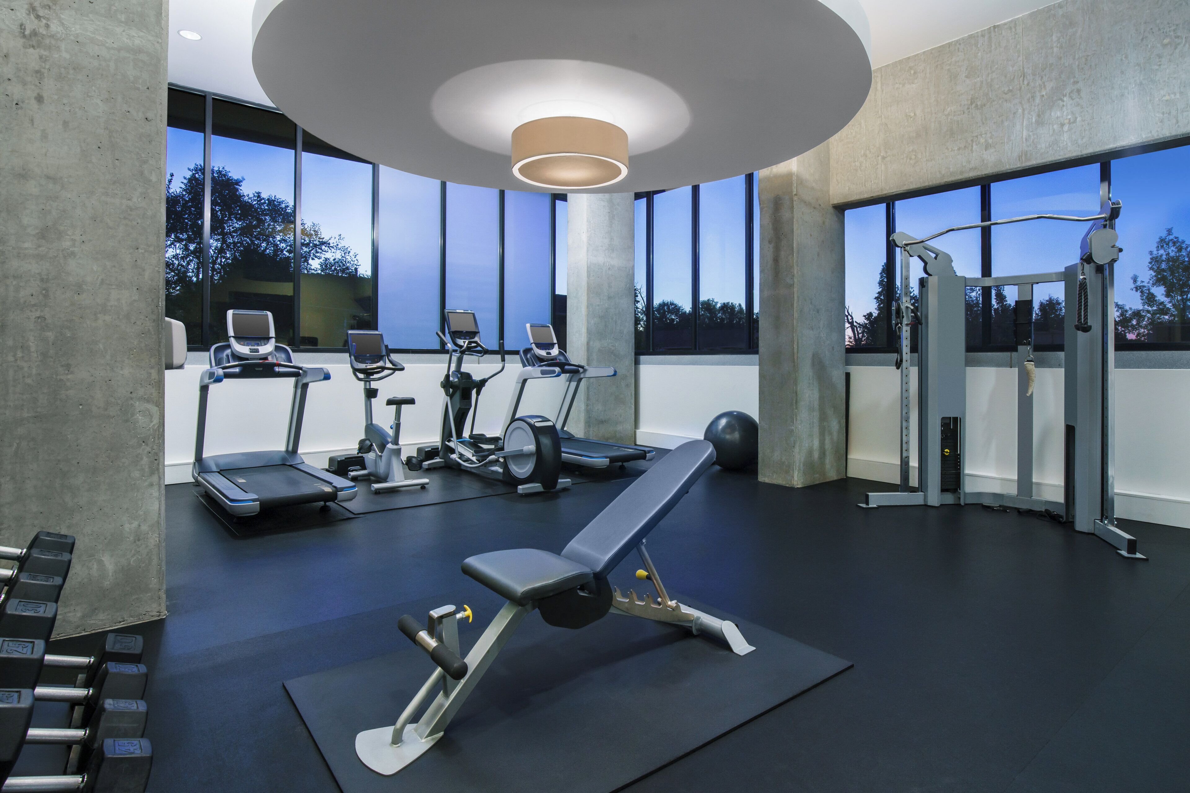 A gym with treadmills, elliptical machines, a bench press, and free weights.