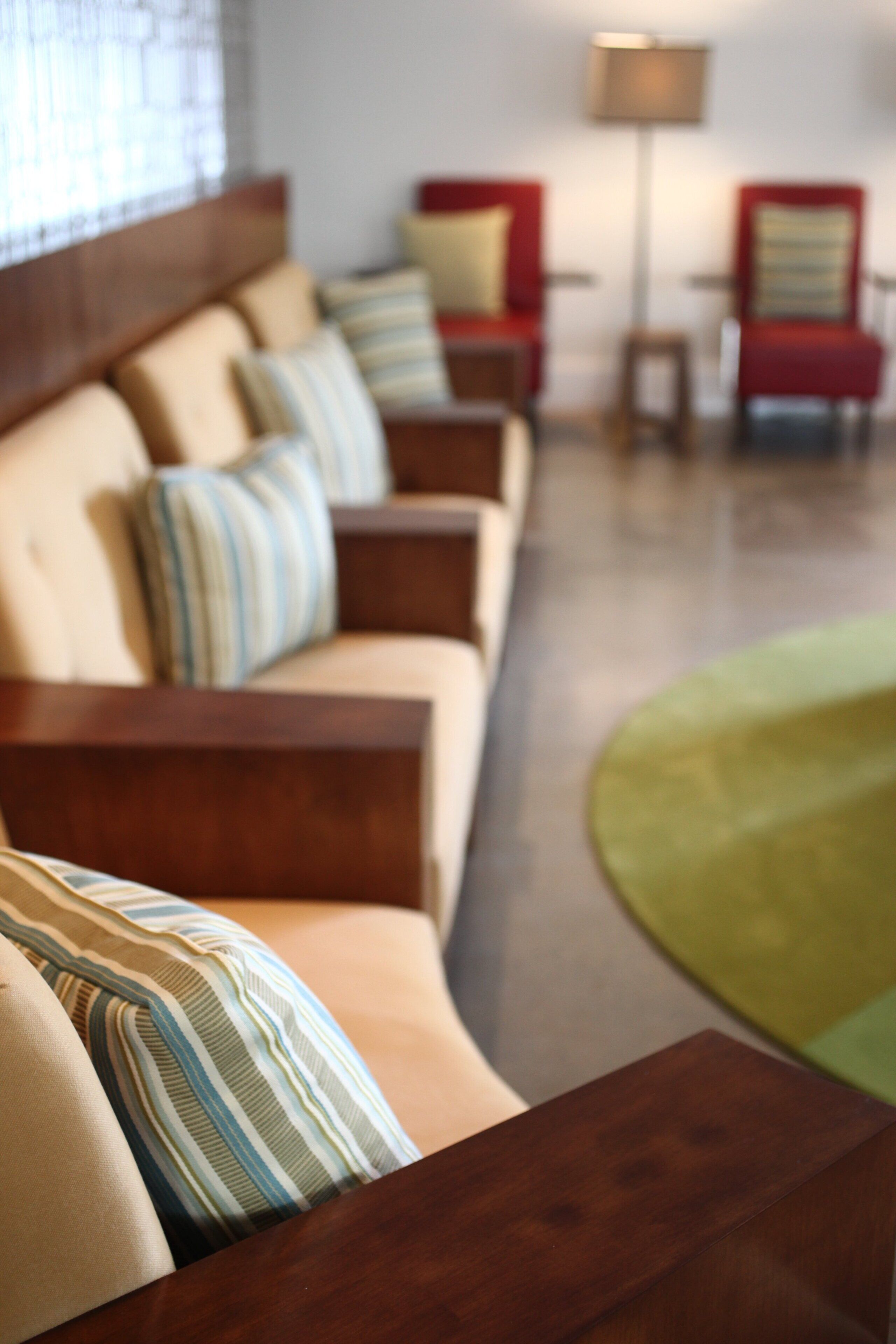 A row of sofas with striped cushions in a room with a wooden floor and a lamp in the background.