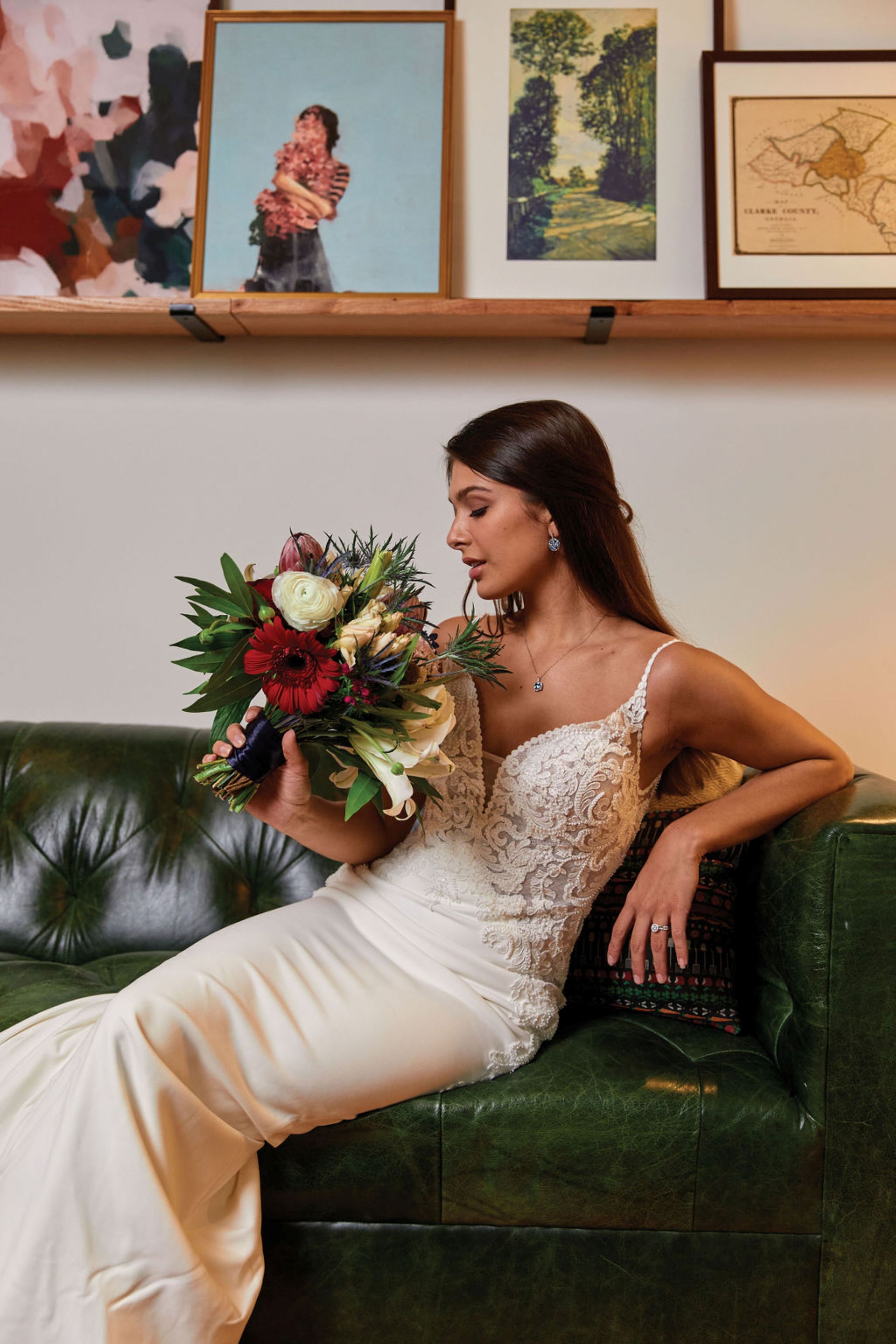 A person seated on a green leather couch holding a bouquet of flowers.