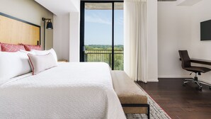 A modern hotel room with a large bed, a desk, and a view of a green landscape through a large window. - Hotel Indigo Athens University Area by IHG (Athens)