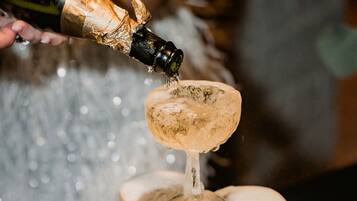 A champagne bottle being poured into a pyramid of champagne glasses.