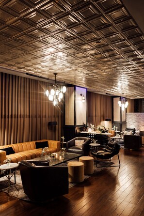 A modern interior with a patterned ceiling, leather sofas, a glass coffee table, and a stone accent wall.
