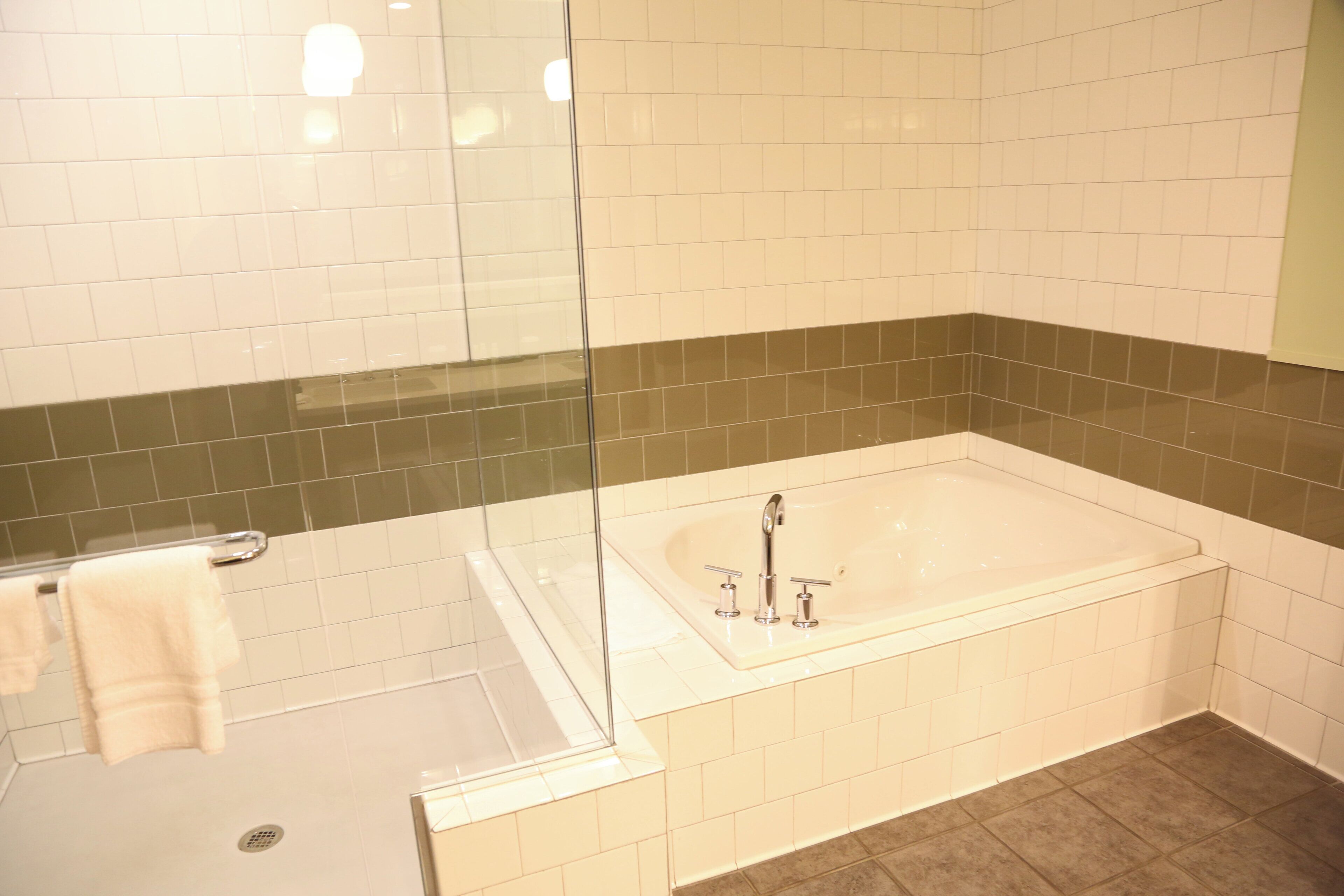 Ein Badezimmer mit einer Duschkabine, einer Badewanne mit zwei Wasserhähnen und einem Handtuchhalter.
