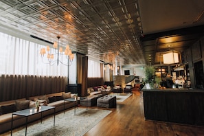 A spacious lounge area with a high ceiling, a bar on the right, and a seating area with sofas and tables.