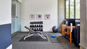 A gym with exercise equipment, a wall-mounted dumbbell rack, and a large exercise ball. - Hotel Indigo Athens University Area by IHG (Athens)