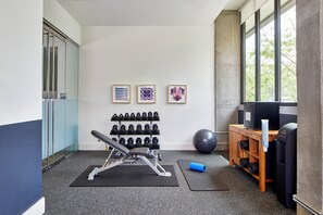 A gym with exercise equipment, a wall-mounted dumbbell rack, and a large exercise ball. - Hotel Indigo Athens University Area by IHG (Athens)