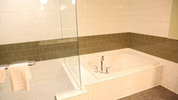 A modern bathroom with a glass-enclosed shower, a freestanding bathtub, and a tiled floor.