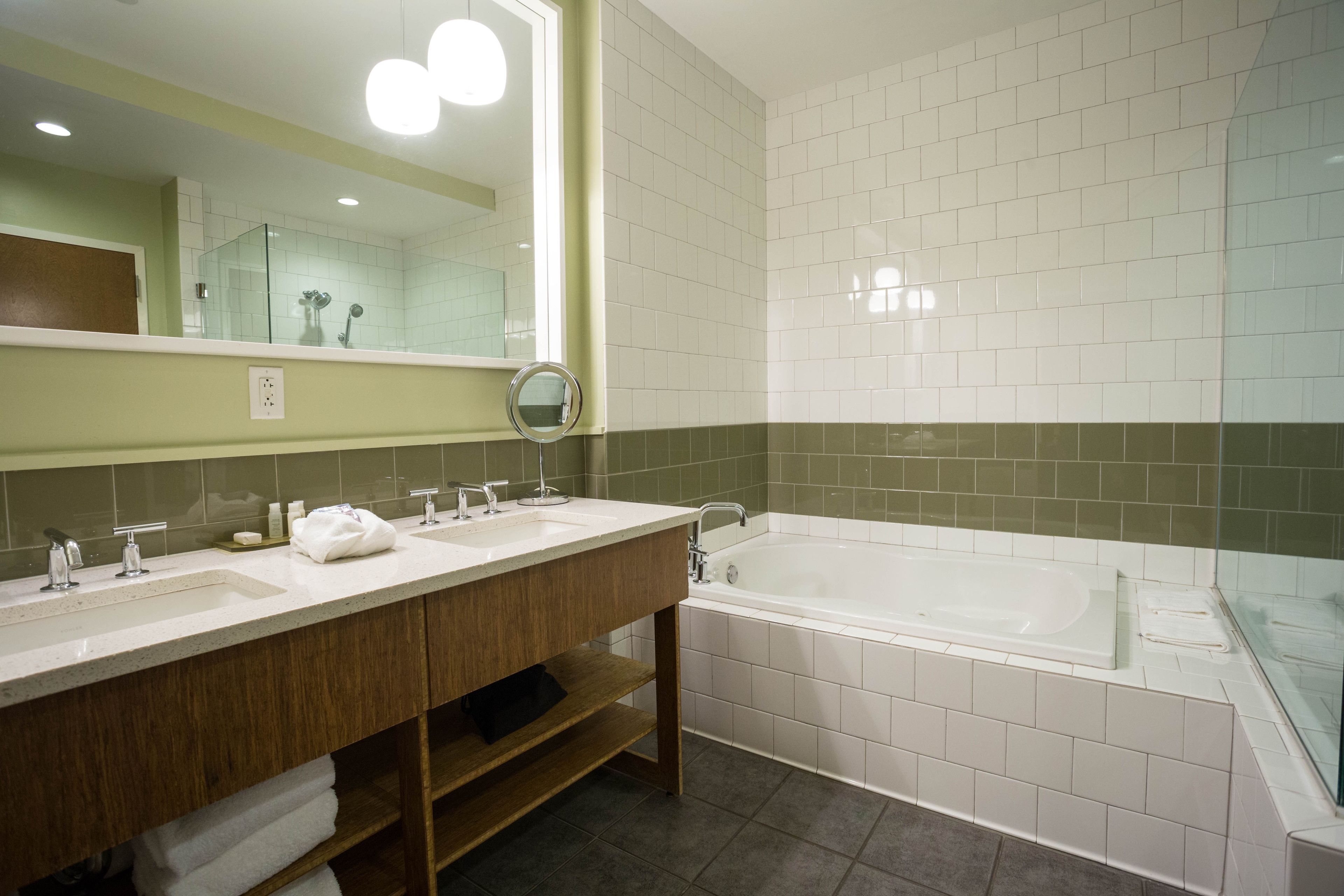 A bathroom with two sinks, a bathtub, and a large mirror.