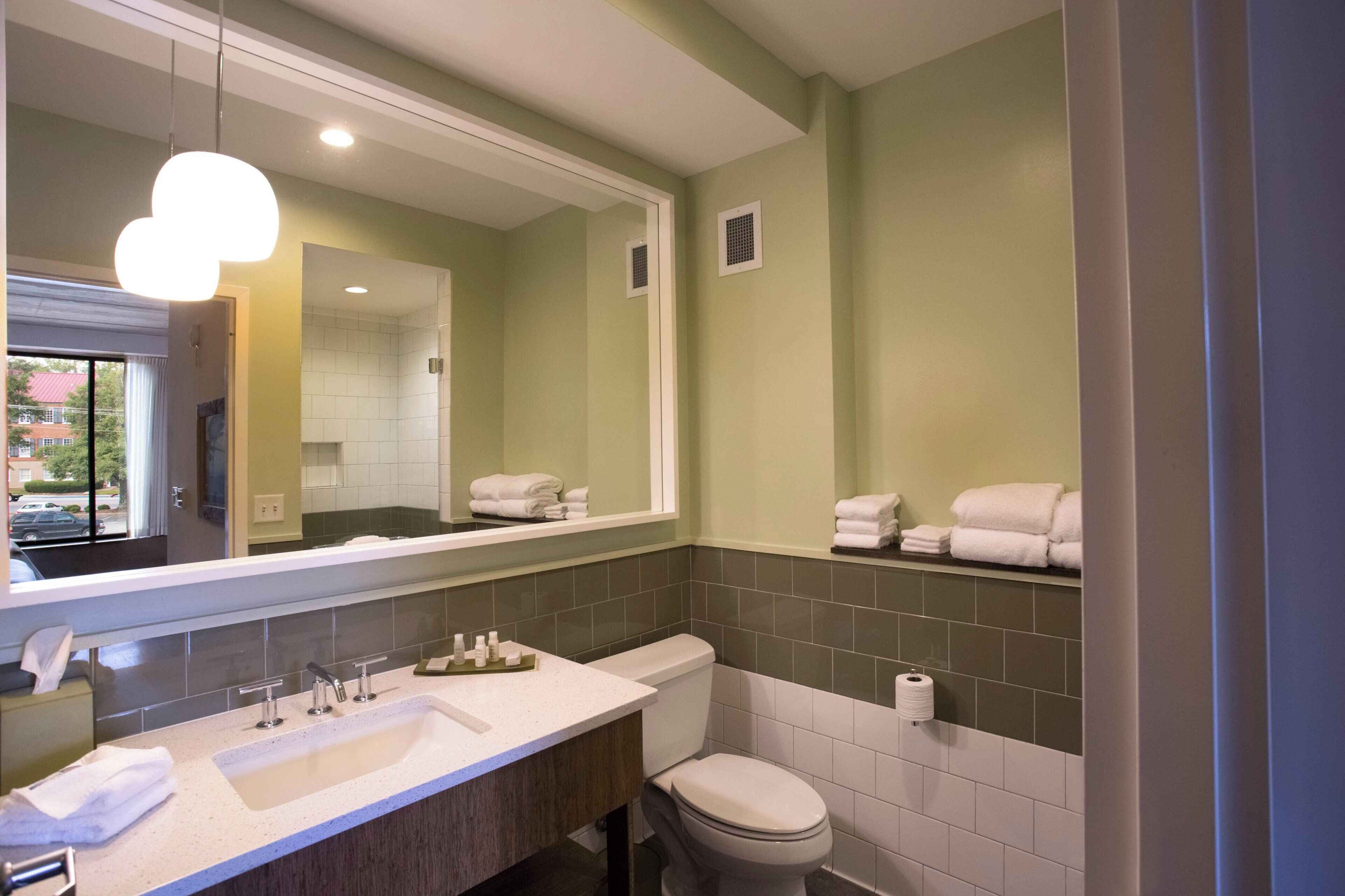 A bathroom with a sink, mirror, toilet, and towel rack.