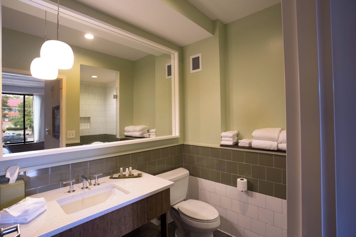 A bathroom with a sink, mirror, toilet, and towel rack.