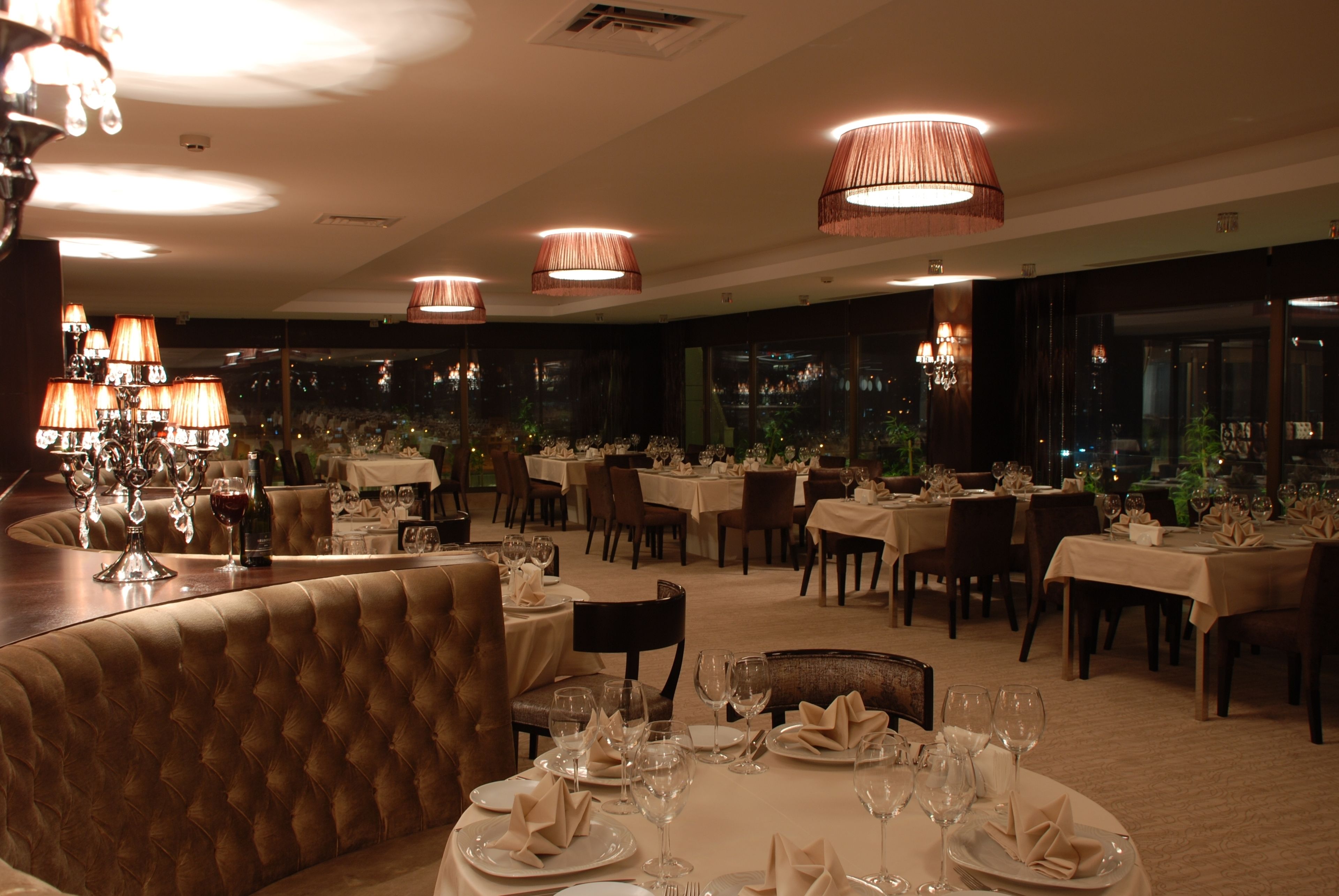 A restaurant with multiple dining tables set for service, featuring a variety of table settings and a bar area with stools.