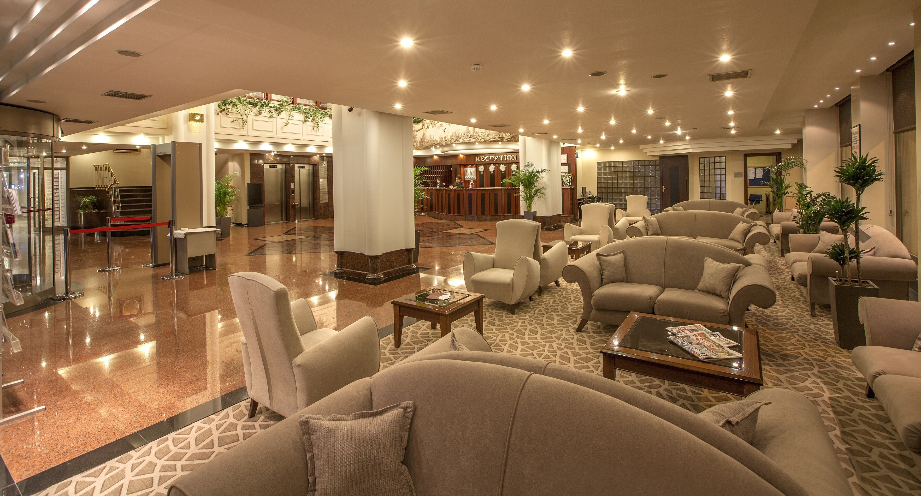 A spacious lobby with multiple seating areas, a reception desk, and a staircase leading to an upper level.