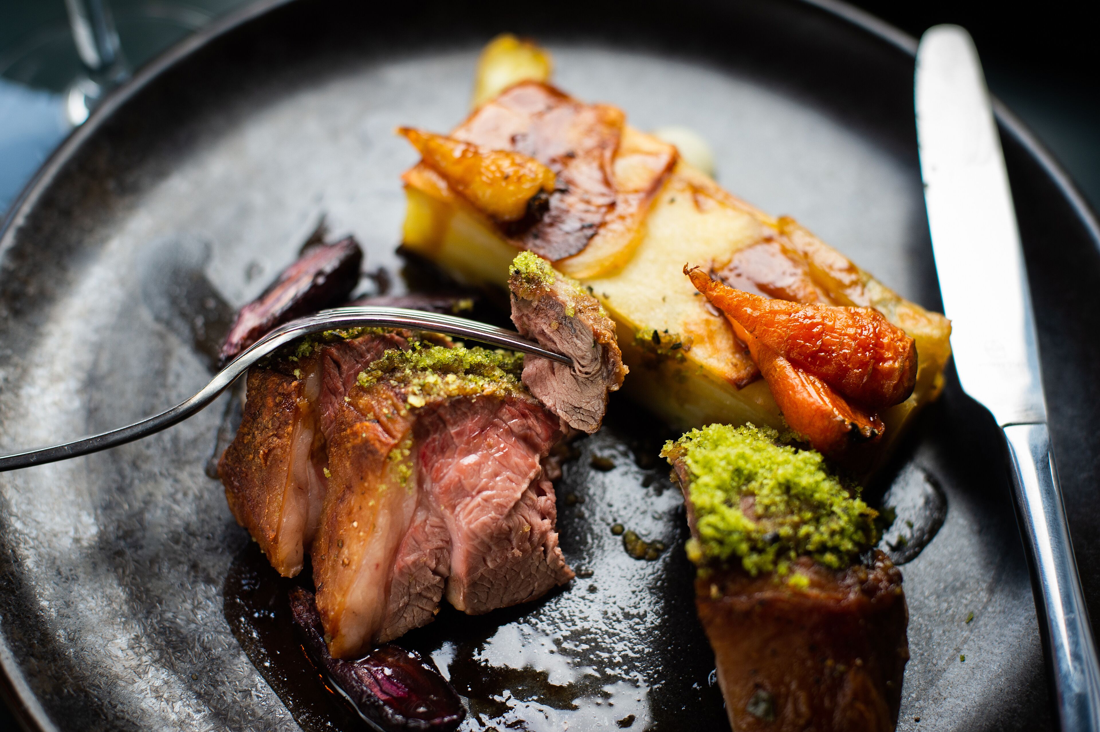 A close-up of a dish with roasted meat and vegetables on a plate.