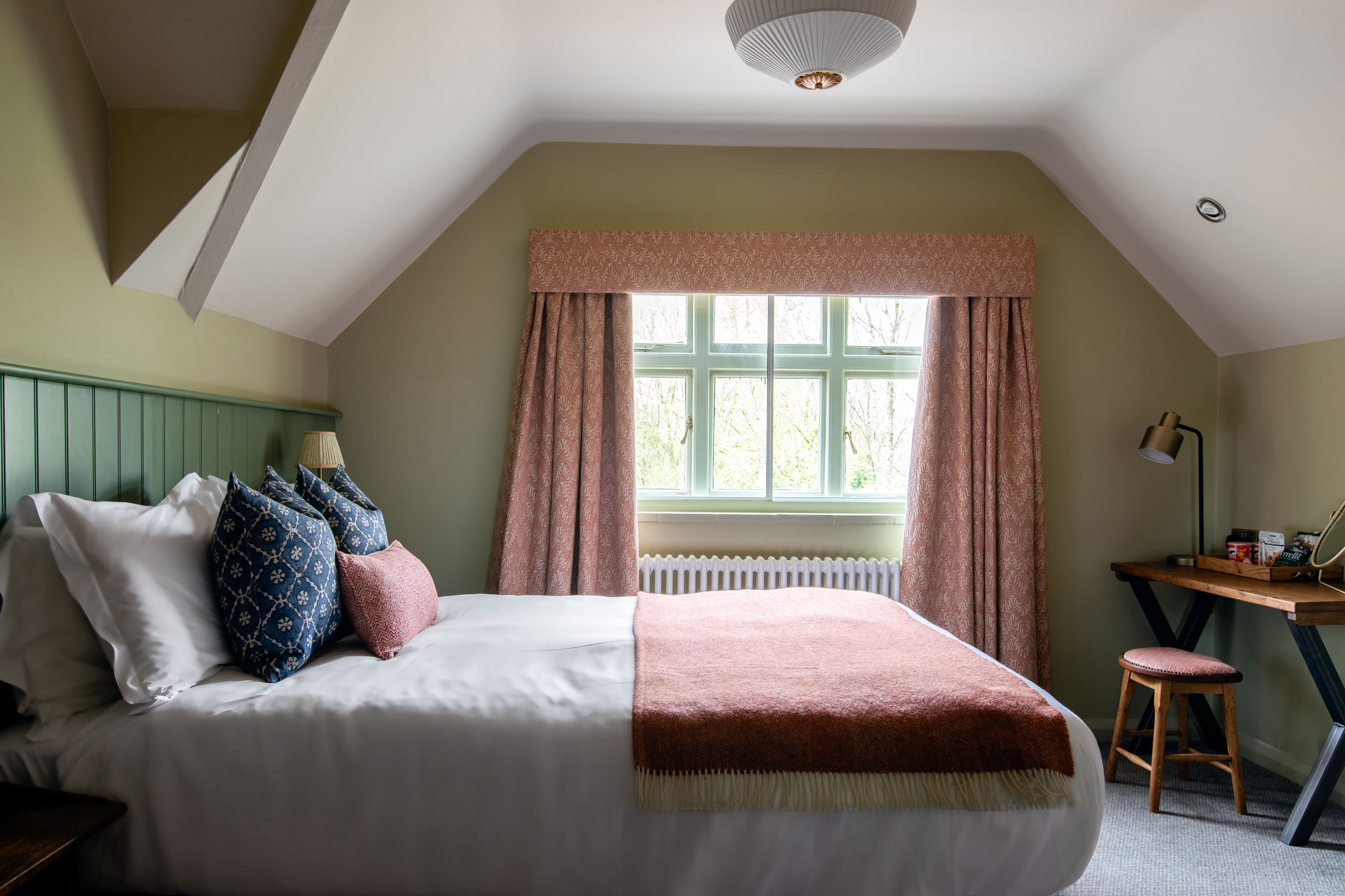 A bedroom with a bed, pillows, a desk, and a chair.