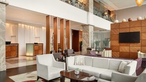 Een ruime lobby met een moderne bank, fauteuils, een salontafel en een receptiebalie.