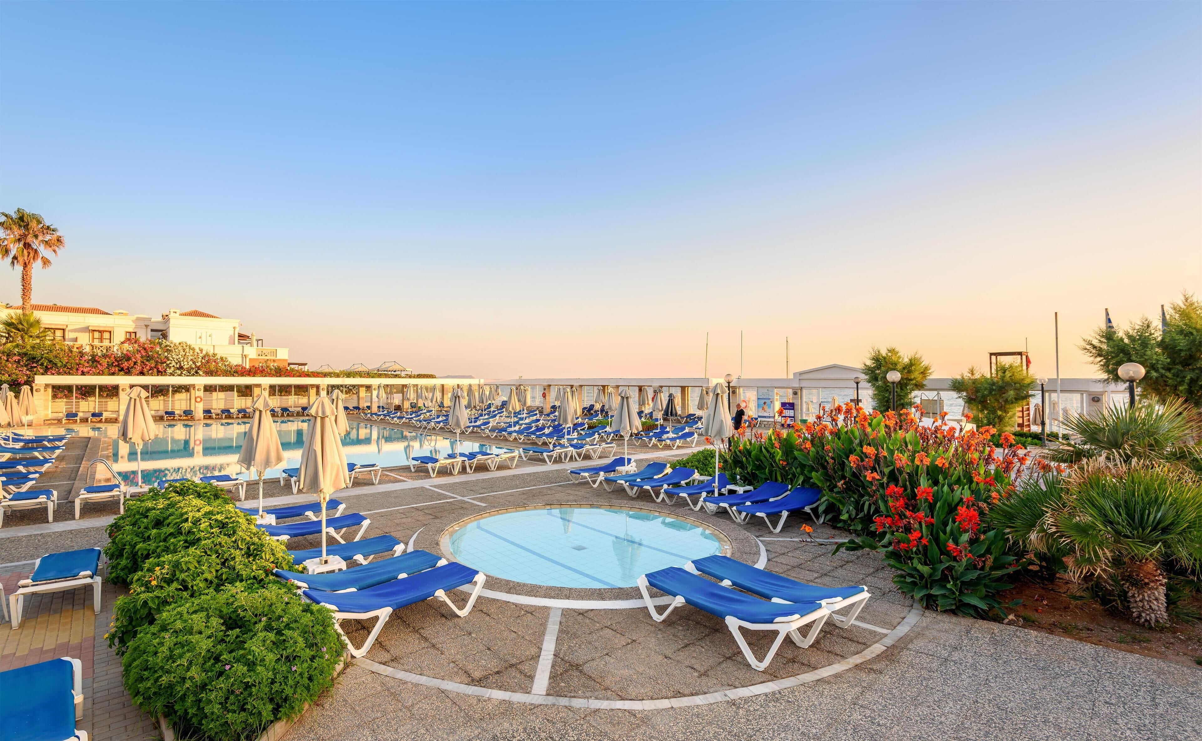 A poolside area with multiple sun loungers and a central pool.