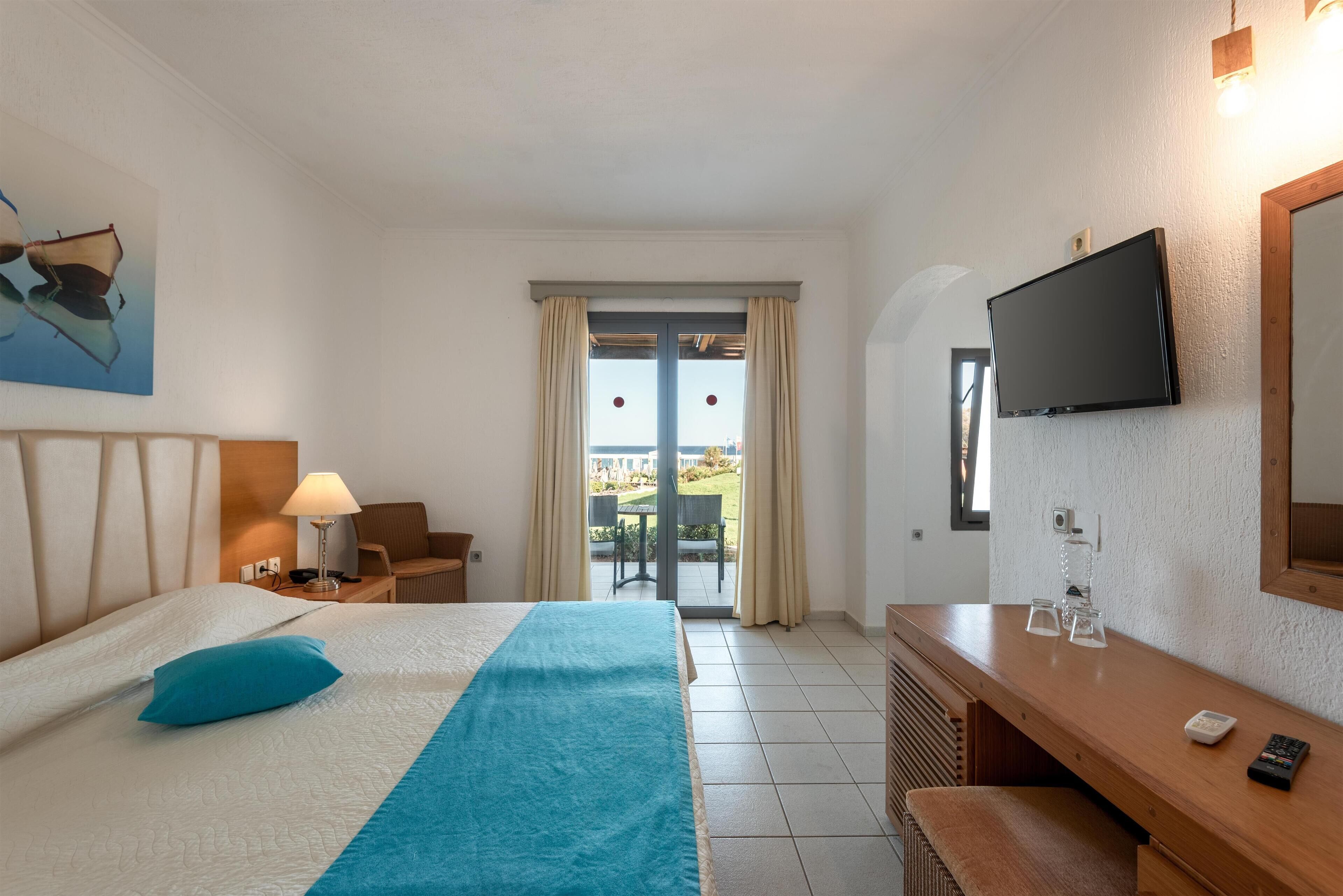 Une chambre d’hôtel équipée d’un lit, d’un bureau, d’une télévision et offrant une vue sur l’extérieur.