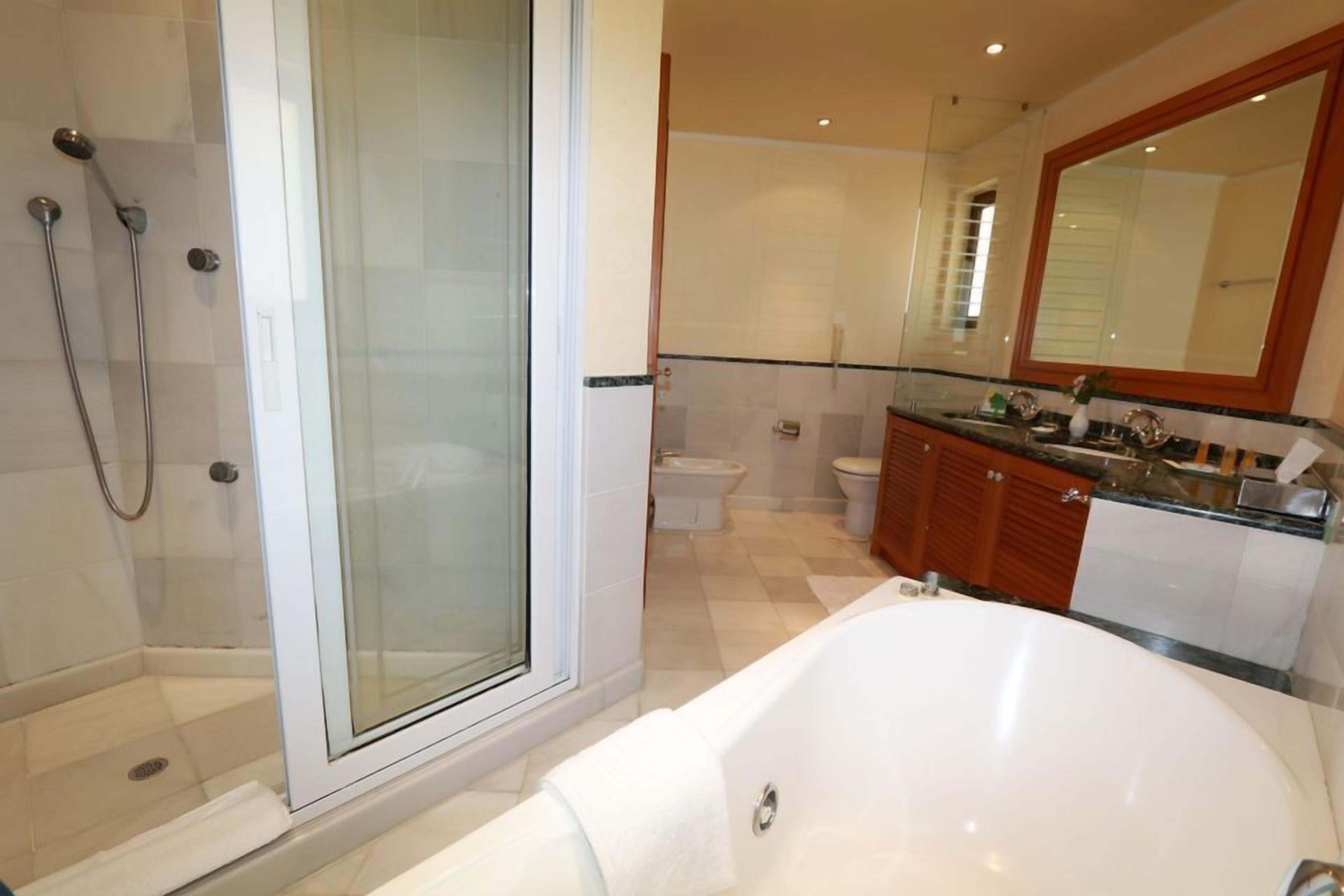 A modern bathroom with a glass-enclosed shower, a freestanding bathtub, and a vanity with a large mirror.