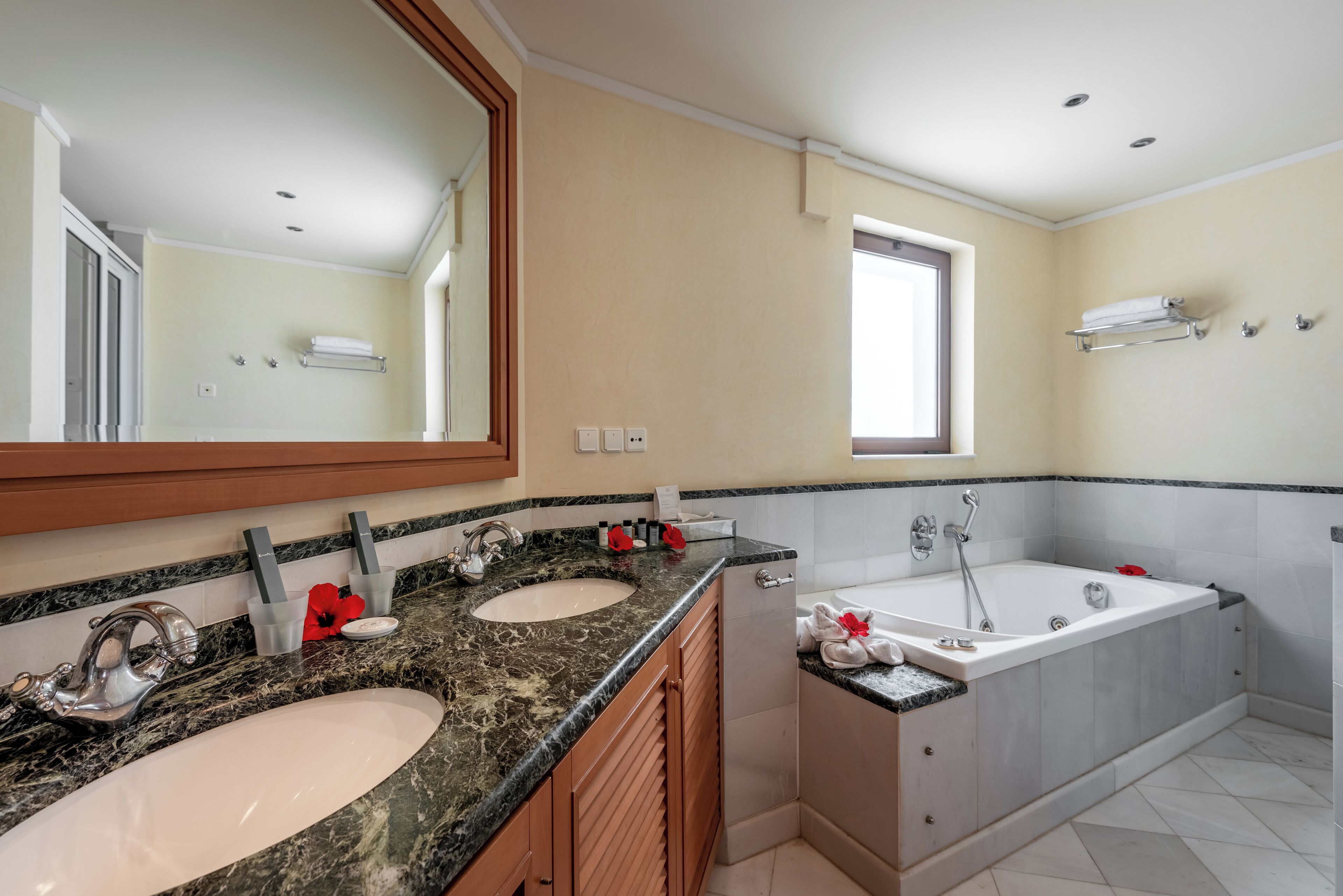 Un baño moderno con dos lavamanos, un espejo grande, una bañera y una ventana que deja entrar luz natural.