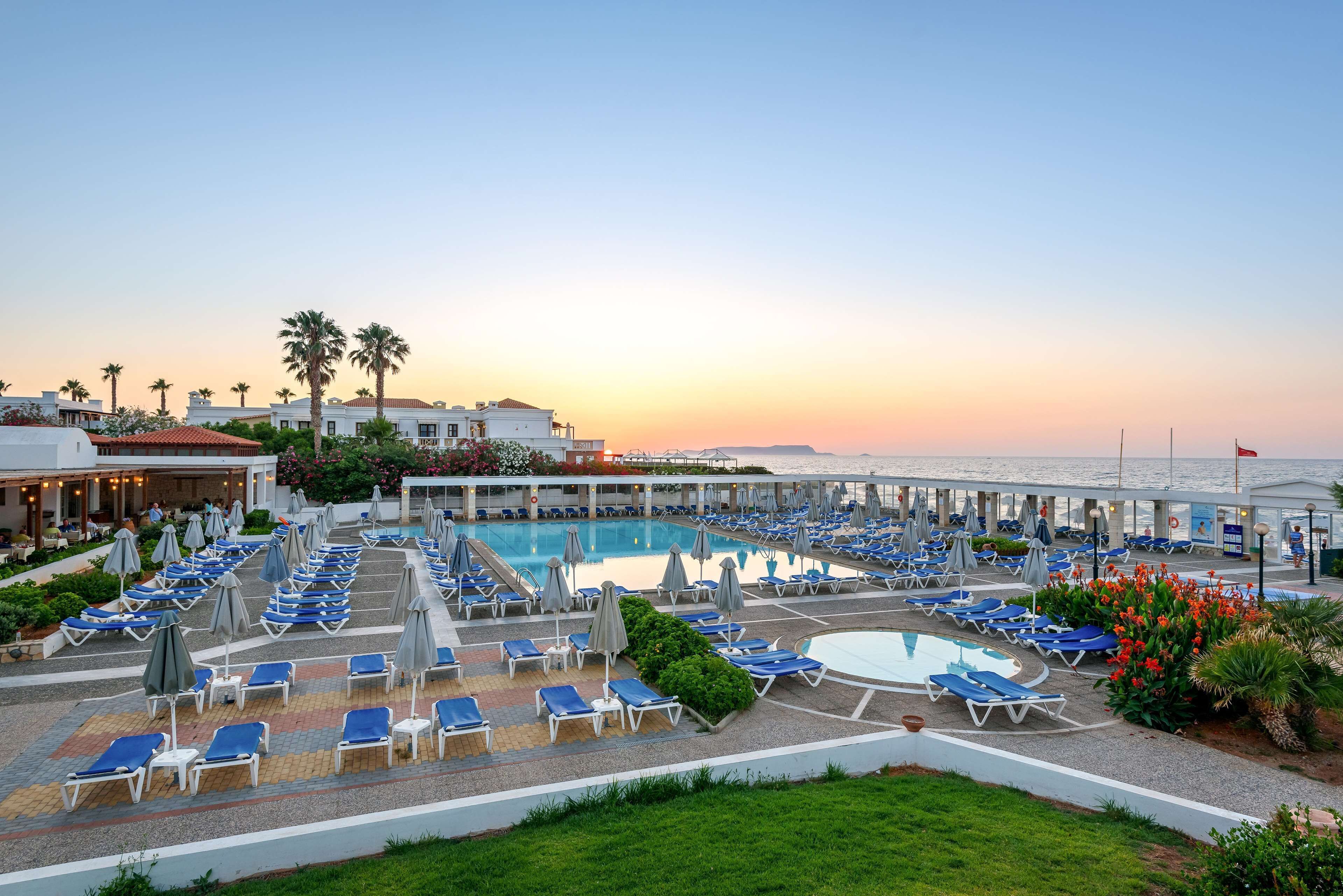 Un resort con zona de piscina, tumbonas y palmeras.