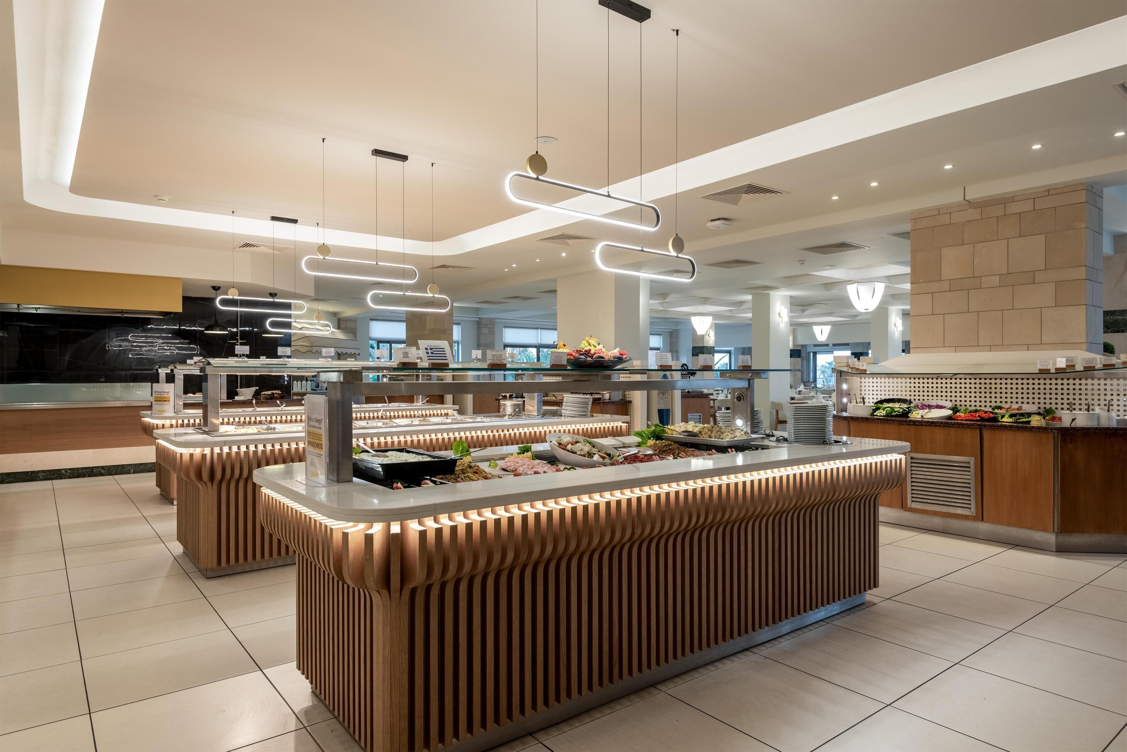 Un espace buffet moderne doté de plusieurs comptoirs de service, d’un éclairage au plafond et d’un sol carrelé, propre et bien entretenu.