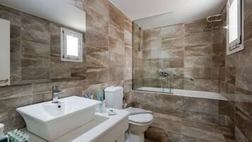A modern bathroom with a large sink, toilet, and glass-enclosed shower area.