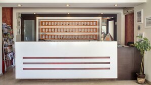 A reception desk with a white counter and wooden shelves above. - Berksoy Hotel (Bergama)
