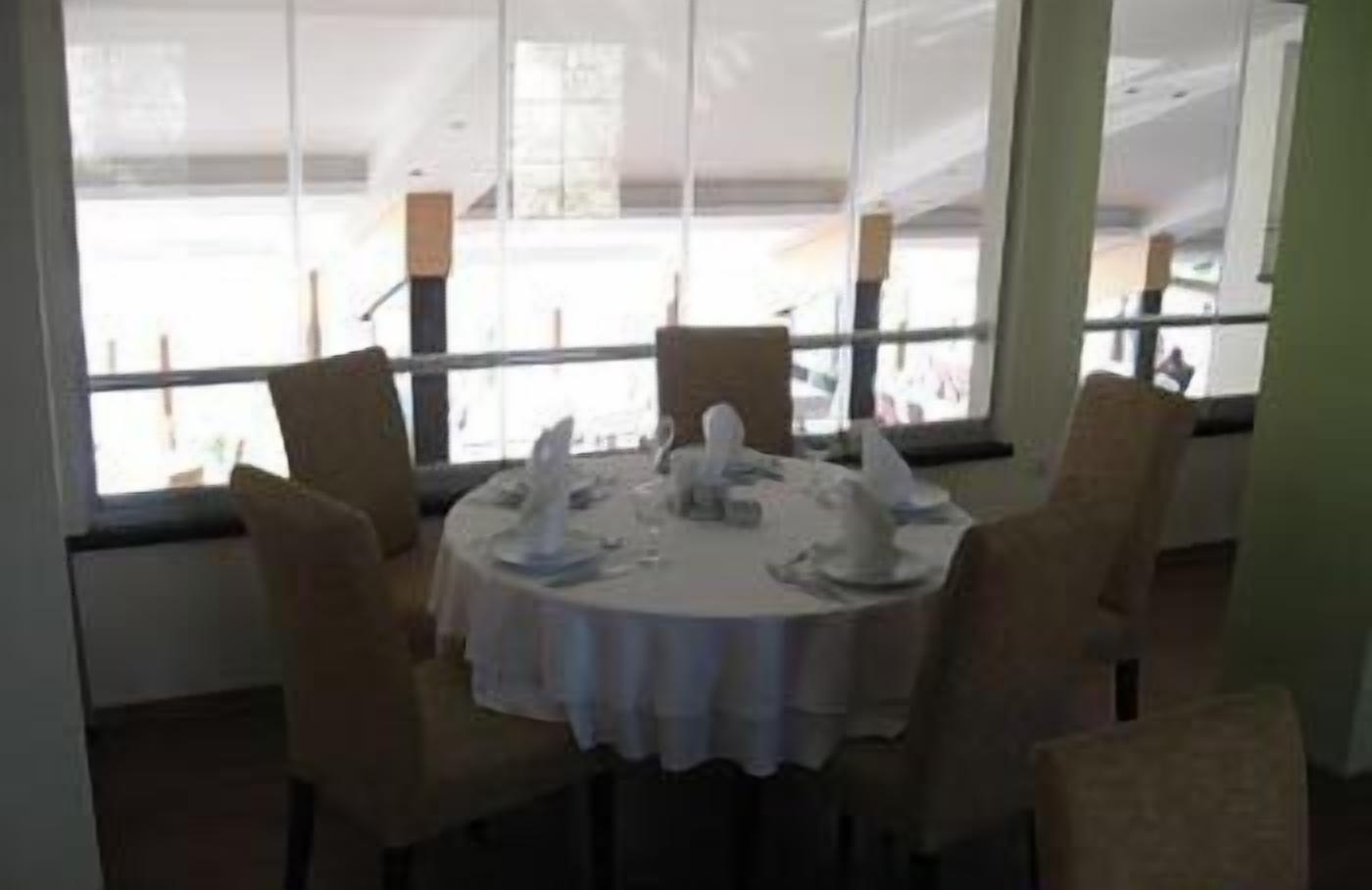 A dining area with a round table set for four, surrounded by chairs.