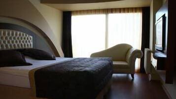 Una habitación de hotel con una cama, una silla, un ventanal grande y un televisor.