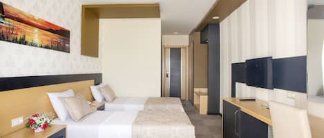 A hotel room with two beds, a desk, a TV, and a painting on the wall.