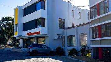 A modern hotel with a two-story structure, a car parked in front, and a cobblestone driveway.